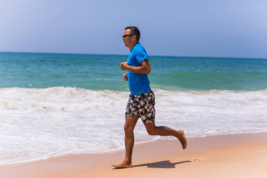 Tropik sahilde koşan adam spor yapmak