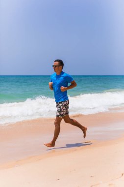 Tropik sahilde koşan adam spor yapmak