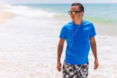 adam mavi deniz ile plaj ve güzel gökyüzü beyaz bulutlar ile yürür. 