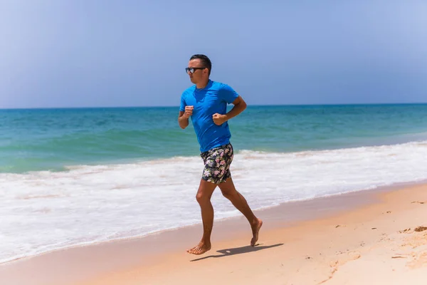 Man running on sunny beach near ocean — Stock Photo, Image