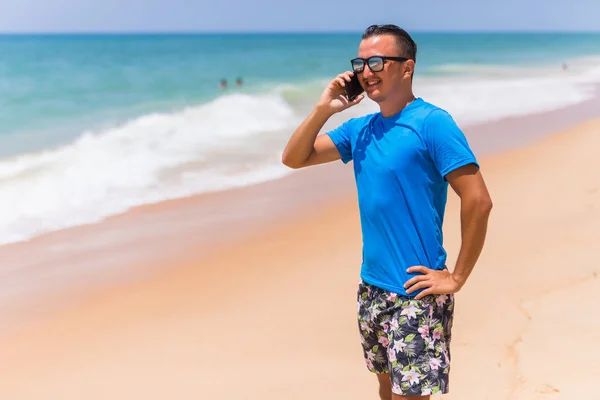 Schöner aktiver Mann mit Smartphone Ozean Hintergrund Rückseite — Stockfoto