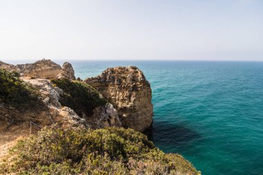 Güzel Atlantik Okyanusu görünümü ufuk kumlu plaj kayalar ve gündoğumu algarve dalgaları