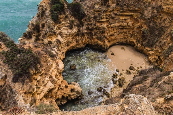 Pasar las vacaciones de verano en vistas al paisaje marino en rocas acantilados con cuevas marinas en la playa de arena — Foto de Stock