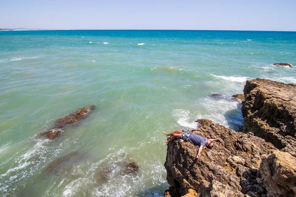 Kayalar uçuruma okyanus algarve Portekiz üzerinde yatan genç adam. Yaz meslek kavramı