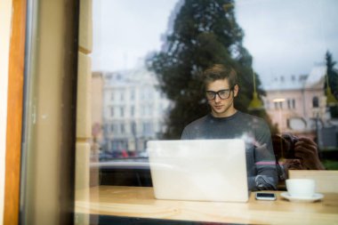 Yakışıklı adam laptop penceresinden kafe görünümünde çalışma