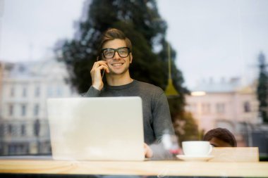 bir kahve dükkanı penceresinde siting ve konuşan yakışıklı adam 