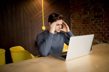 Üzgün yüz ya da baş ağrısı laptop çalışma ile dizüstü çalışan yakışıklı genç 