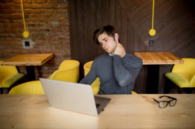 Yakışıklı adam dizüstü ofiste boyun ağrısı muzdarip