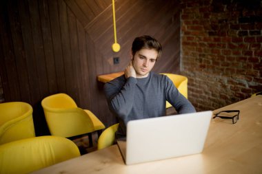 Yakışıklı adam dizüstü ofiste boyun ağrısı muzdarip