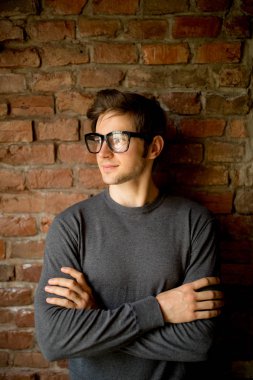 Kollarını bir tuğla karşı çarpı işareti ile ayakta bir raslantı giyimli genç işadamı portresi