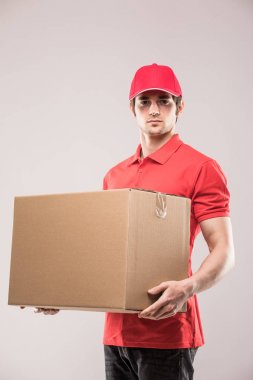 Bir karton kutu tutarak ve Grey dururken gülümseyen neşeli teslimat adam mutlu genç kurye