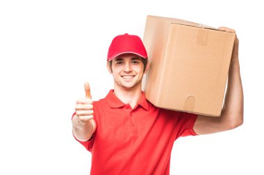 Başparmak gösterilmesini ve ayakta beyaz arka plan üzerinde izole karton kutular yakınındaki gülümseyen teslimatçı