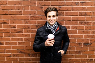 Yakışıklı adam akıllı rahat kıyafet kahve tuğla duvara holding