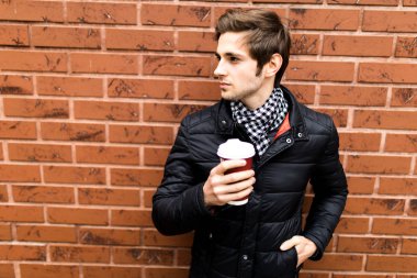 Yakışıklı adam akıllı rahat kıyafet kahve tuğla karşı holding