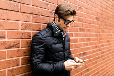 Metin iletisi yan görünüm yakışıklı genç adam cep telefonu tutan akıllı rahat kıyafet içinde yazarak