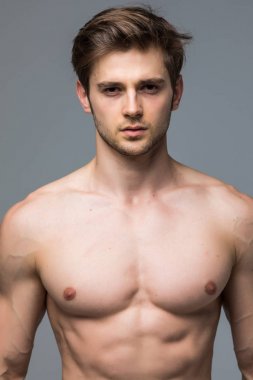 Yakışıklı delikanlı ile çıplak gövde kameraya gri arka plan üzerinde seyir 