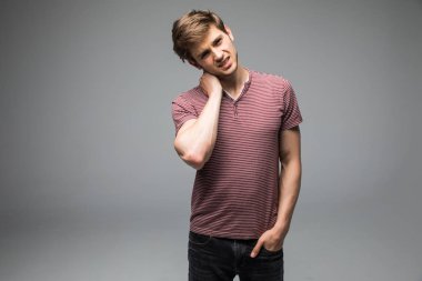 Casual beyaz t gömlek gri arka plan karşı boyun ağrısı muzdarip üzgün mutsuz genç adam