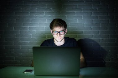 Internet'e bağlanma ve gece geç saatlerde bir dizüstü bilgisayar kullanarak gülümseyen genç adam