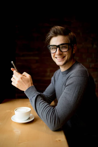 Homem com telefone digitando ou sentado em rede social beber café no café — Fotografia de Stock