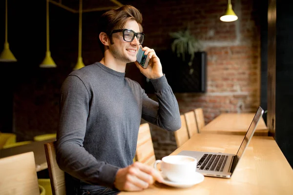 Göz gözlük yakışıklı freelancer konuşmak smartphone laptop süre