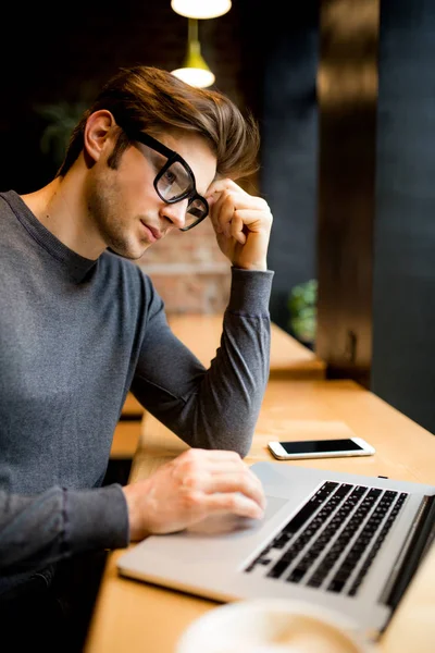 Confundido con las manos en la cabeza joven freelancer delante de un ordenador portátil — Foto de Stock