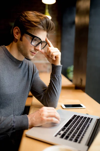 Confuso com as mãos na cabeça jovem freelancer na frente de um laptop — Fotografia de Stock