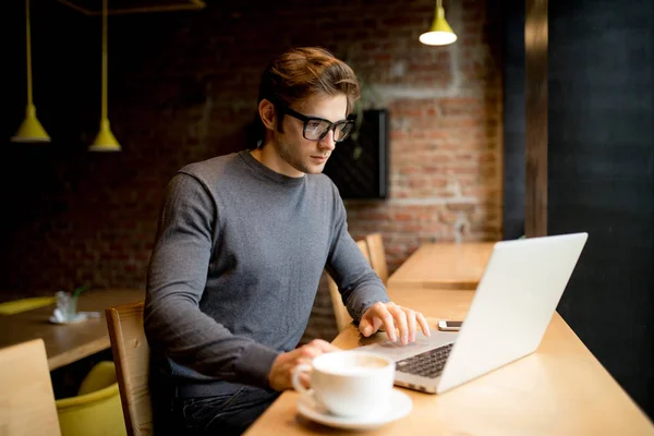 Hombre de negocios vista lateral con camisa sentada en la mesa en la cafetería y utiliza el ordenador portátil — Foto de Stock