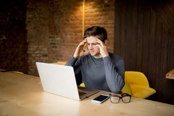 Przystojny młody mężczyzna pracujący w laptopa z smutną twarz lub ból głowy, praca w laptopie — Zdjęcie stockowe