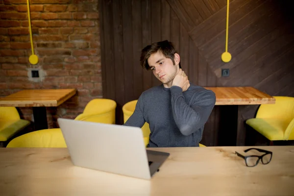 Bonito homem sofrendo de dor no pescoço no escritório no laptop — Fotografia de Stock