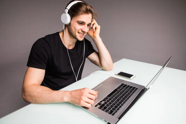 Boa música aumenta minha produtividade jovem sério em fones de ouvido trabalhando no laptop enquanto sentado no escritório — Fotografia de Stock