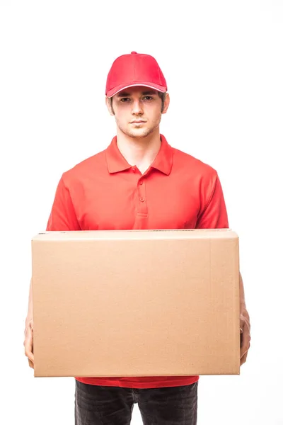 Alegre repartidor feliz joven mensajero sosteniendo una caja de cartón y sonriendo mientras está de pie sobre fondo blanco — Foto de Stock
