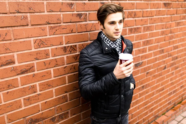 Genç yakışıklı adam portresi fincan kahve tuğla duvar ile