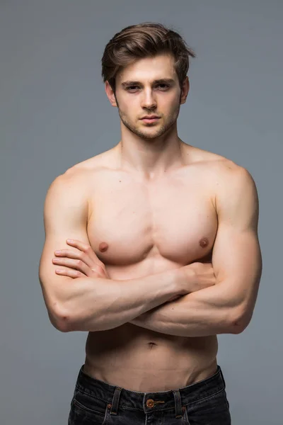 Kas atlet vücut geliştirmeci adam gri bir arka plan üzerinde çıplak bir gövde ile