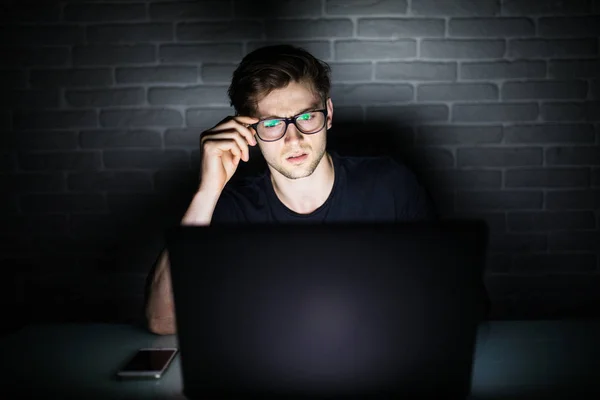 Człowiek pracuje na laptopie w nocy ręce na okulary — Zdjęcie stockowe