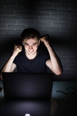 Yatakta muzaffer bir hareketi ile neşeli adam adam bilgisayar başında zafer hareketlerle heyecanlı