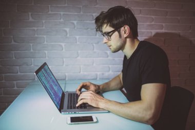 Genç adam akmak gece iş üstünde laptop ve ağ kesmek. Genç hacker saldırı gece bir ağda
