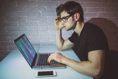 Genç adam akmak gece iş üstünde laptop ve ağ kesmek. Genç hacker saldırı gece bir ağda