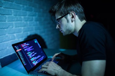 Dizüstü bilgisayar saldırı ağ yazılımı gece çalışan genç adam hacker 