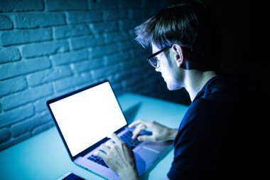 Gecenin beyaz ekranlı dizüstü bilgisayar kullanan adam. Laptop genç hacker çalışmalarında gece