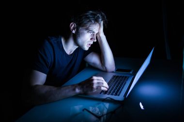 Gece önünde in laptop otururken hayal kırıklığına uğramış genç adam duygu yorgun 