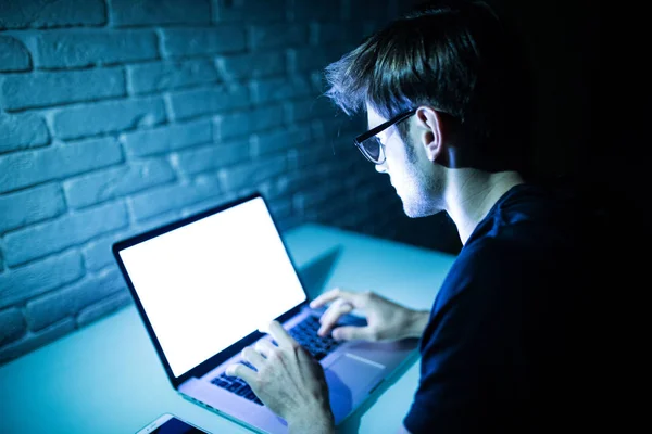 Hombre usando el ordenador portátil en la noche con pantalla blanca. Joven hacker trabajo en el ordenador portátil en la noche — Foto de Stock