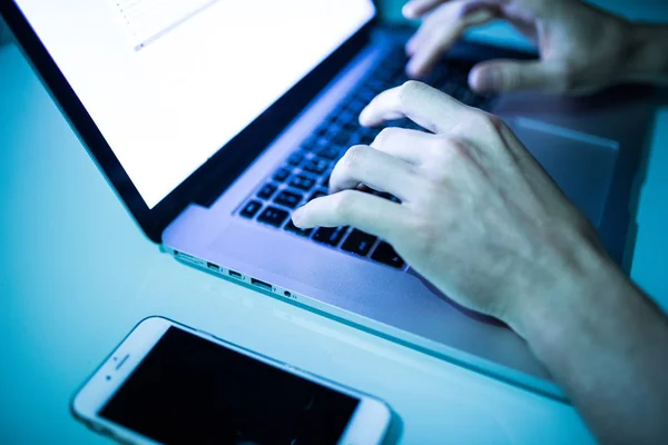 Primer plano de las manos masculinas escribiendo en el teclado con pantalla blanca en la noche — Foto de Stock