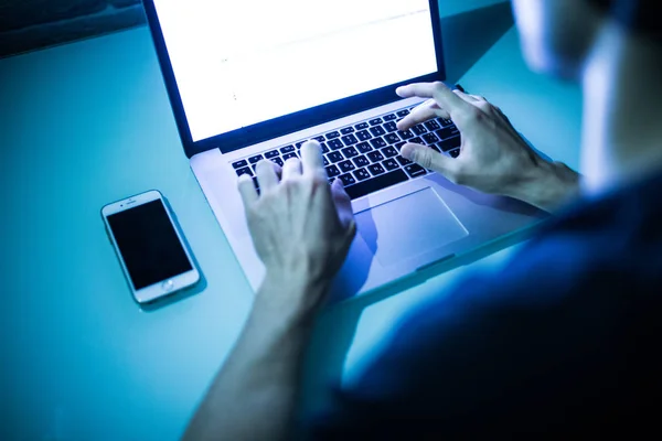 Primer plano de las manos masculinas escribiendo en el teclado con pantalla blanca en la noche — Foto de Stock
