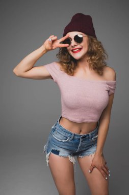 Portre stüdyo güzel hipster genç kız el barış kare somurtarak bere şapka ile vurdu. 