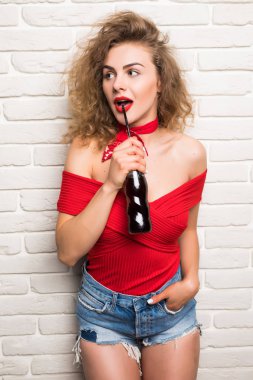 Şık genç kız duvara karşı bir şişe soda su tutuyor