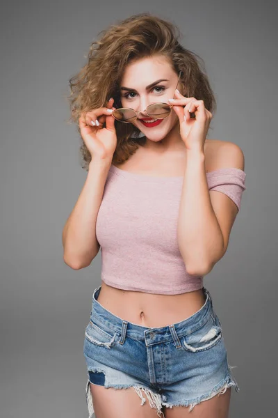 Stylish hipster fashion portrait of trendy casual young woman wearing glasses on gray — Stock Photo, Image