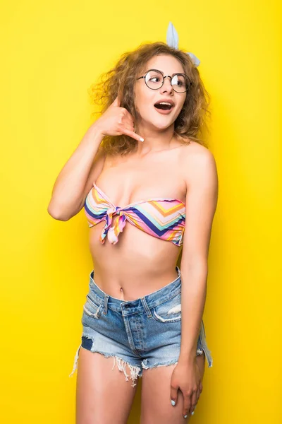 Beauty portrait of a happy young curly joyfull woman show call me back over yellow background — Stock Photo, Image