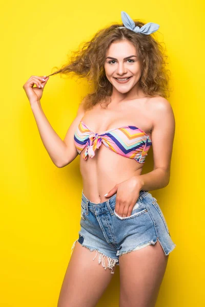Fiatal hűvös göndör fiatal nő, sárga háttér — Stock Fotó