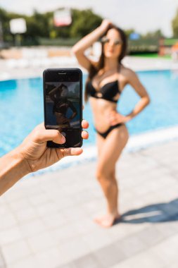 El telefon ile mayo Yüzme Havuzu yakınındaki güzellik seksi kadın fotoğrafı al. Yaz fotoğraf süre.