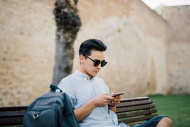 Asya yakışıklı şehrin bankta oturmuş akıllı telefonuna mesaj yazarak